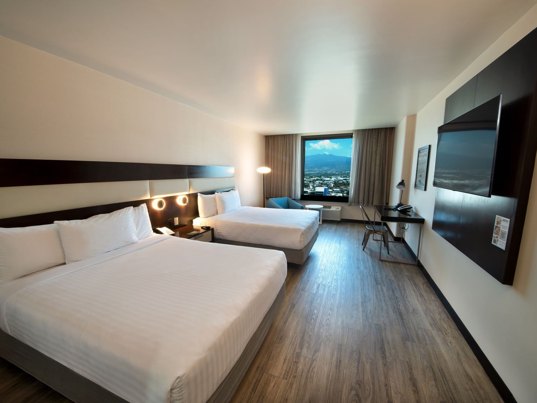 Queen Bed Panoramic View with two bed, TV, chair by window and work desk at D Sabana Hotel, San Jose Costa Rica Hotel