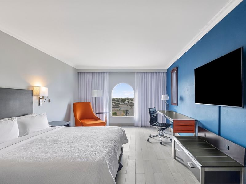 Habitación Superior, 1 King en Fiesta Inn Express Nuevo Laredo con pared azul, TV y sillón junto a ventana arqueada