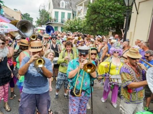 Festive parade with a group of musicians playing trombones and trumpets near La Galerie Hotel