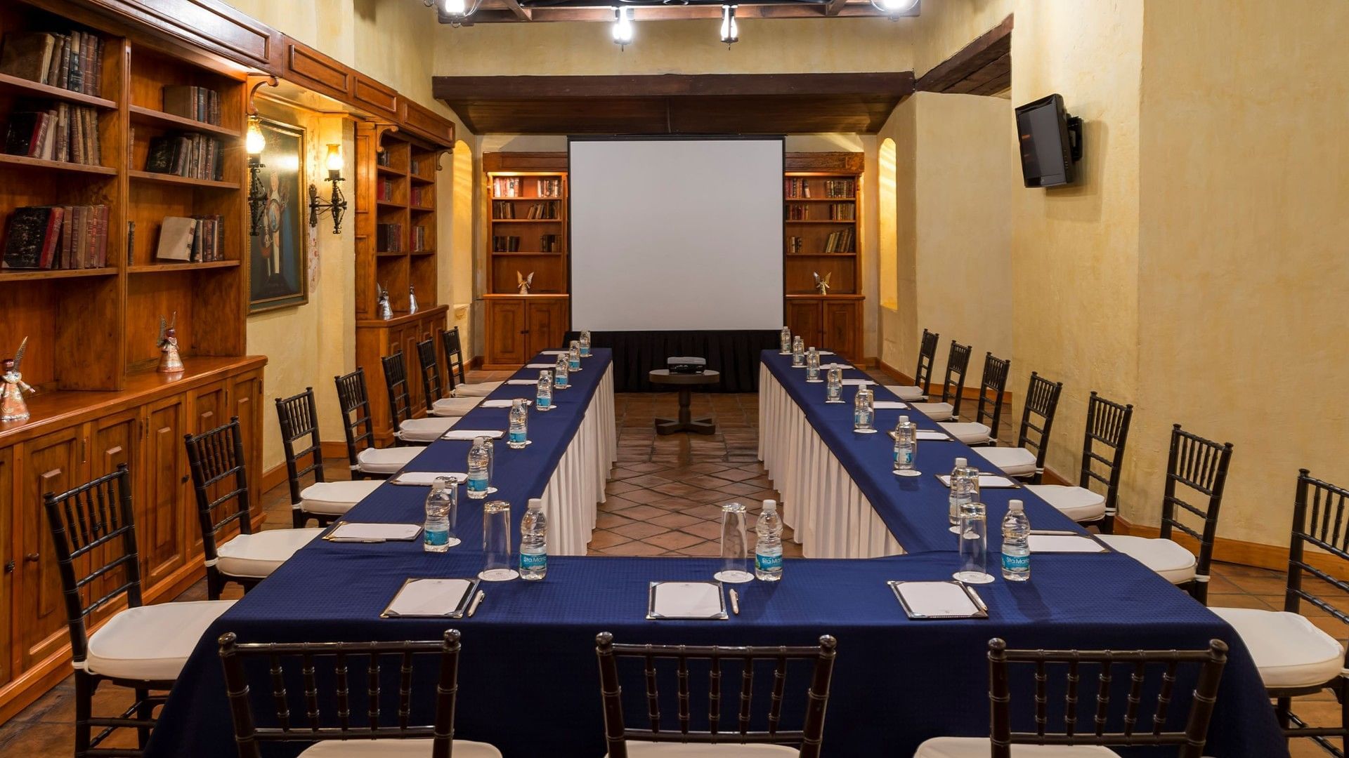 U-shaped conference room setup with a royal blue tablecloth, notepads, and water bottles at Quinta Real Oaxaca