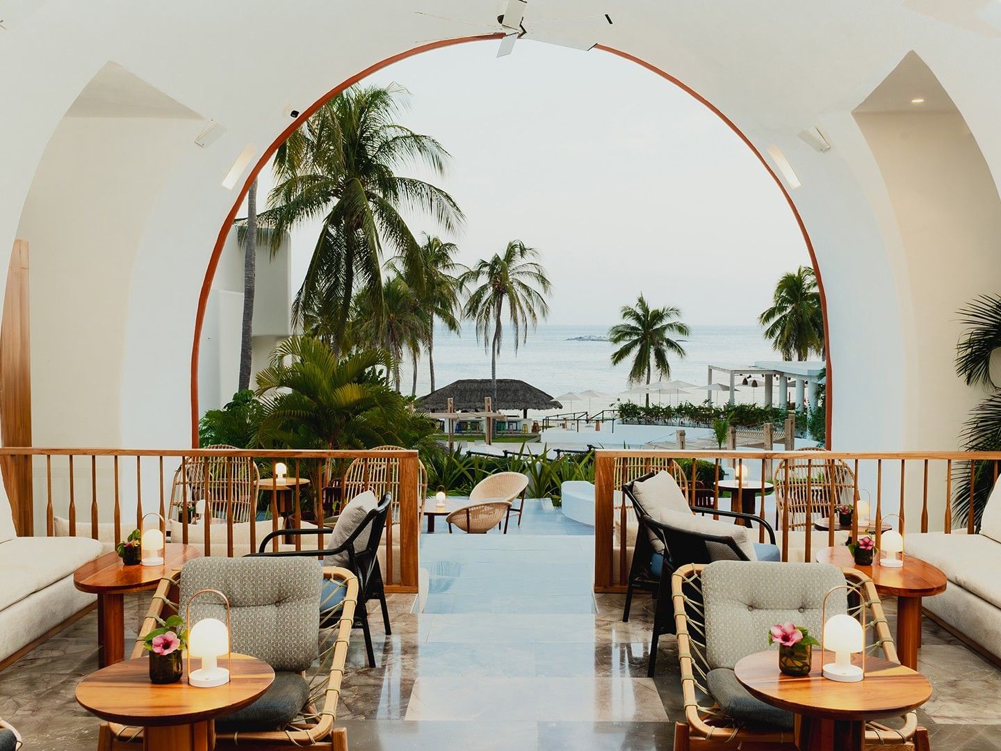 Dining area with plush seating and a large white arch, overlooking the ocean in Chez Binni at Camino Real Zaashila Huatulco