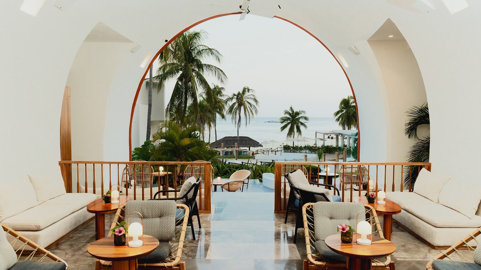 Dining area with plush seating and a large white arch, overlooking the ocean in Chez Binni at Camino Real Zaashila Huatulco