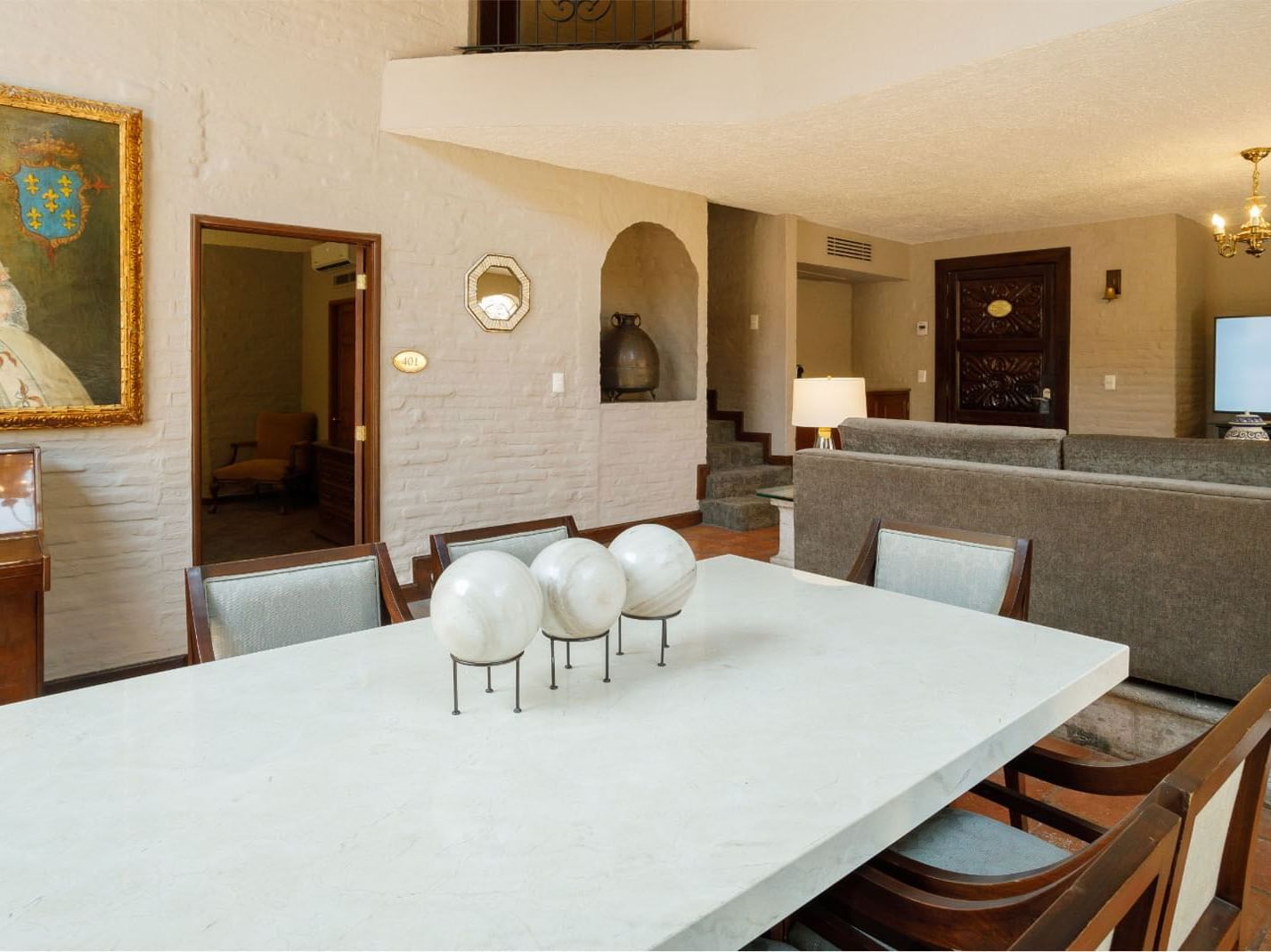 King Presidential Suite dining area with stone walls, white marble table, and oil paintings at Quinta Real Guadalajara