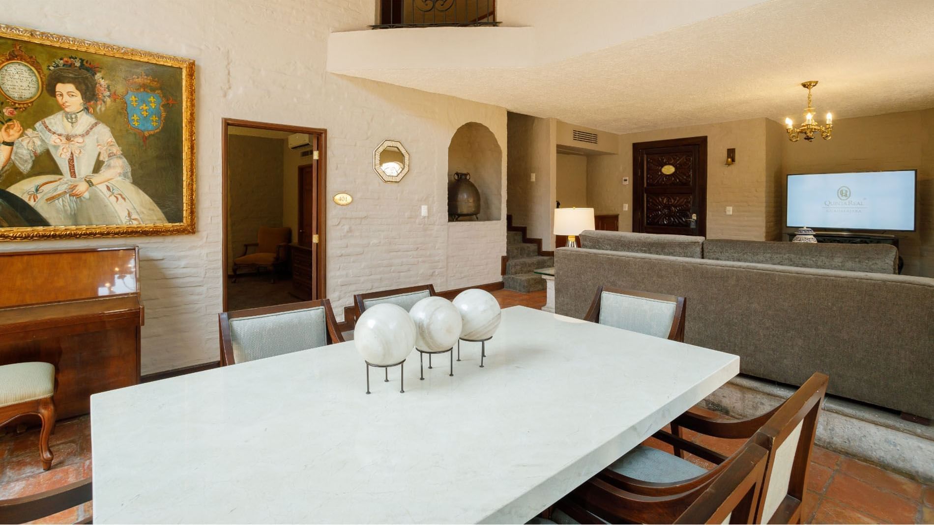 King Presidential Suite dining area with stone walls, white marble table, and oil paintings at Quinta Real Guadalajara