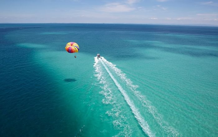 A person gracefully parasails above the sparkling ocean near Grand Park Kodhipparu, Maldives