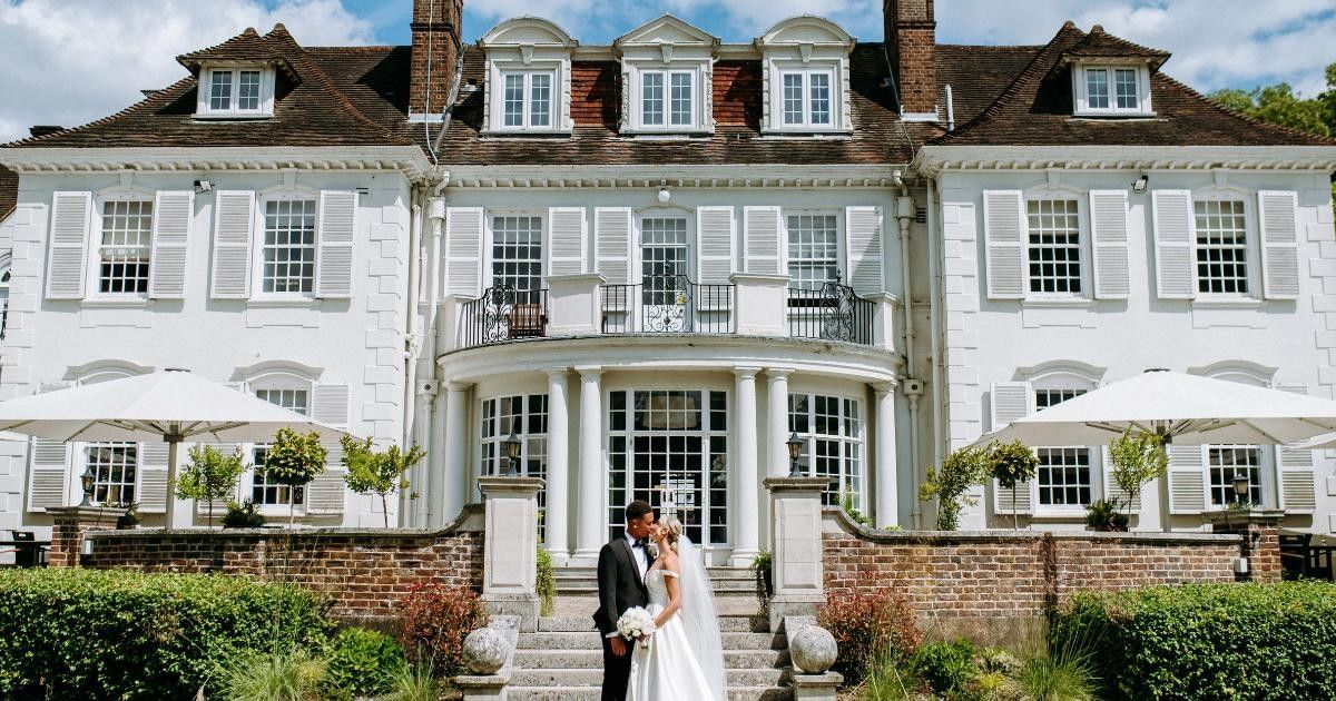 Bride and groom outside of mansion as we promote our surrey wedding fair at Gorse Hill