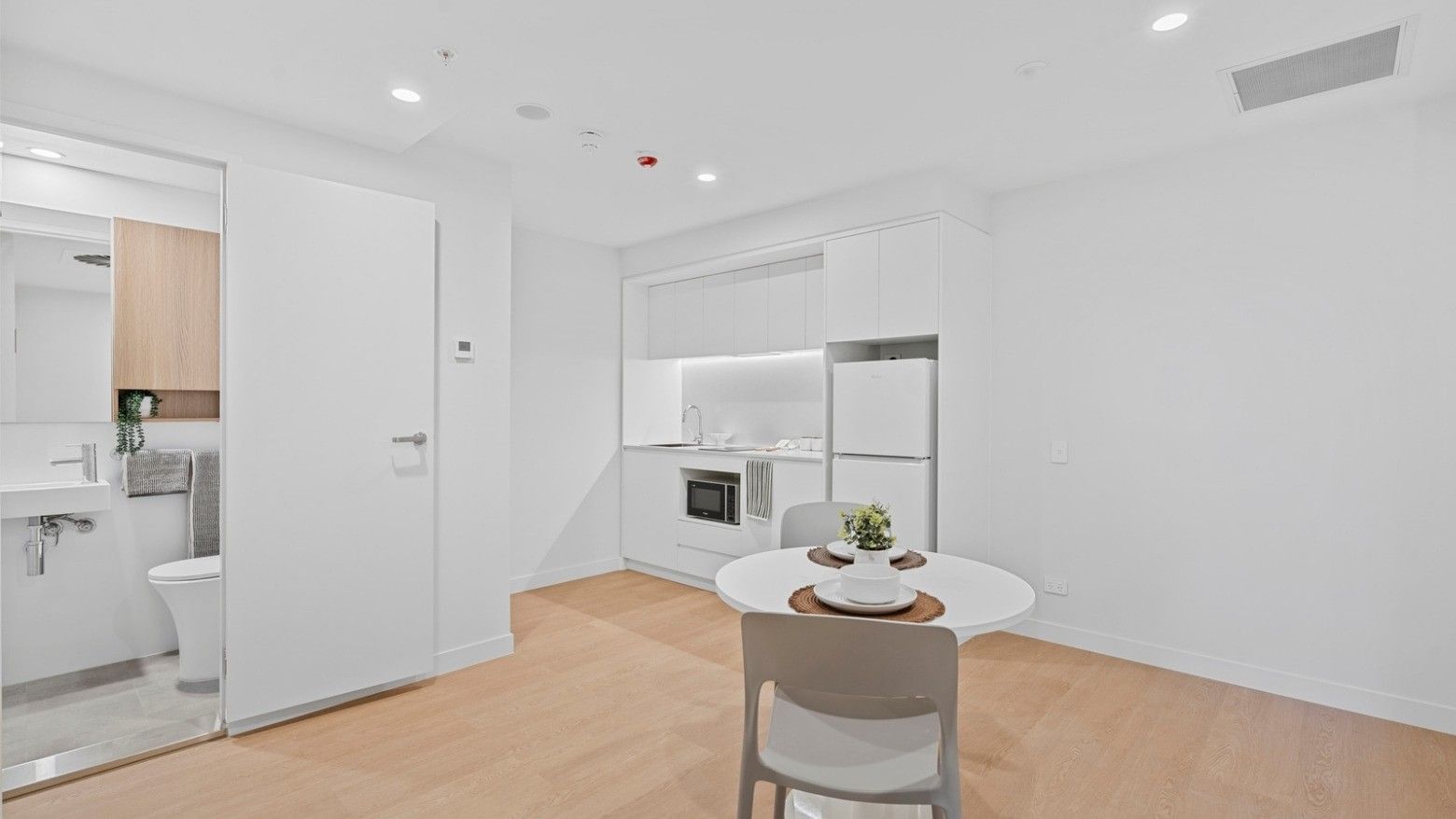 Modern apartment interior with white furniture and wooden floors at UniLodge Brisbane City.