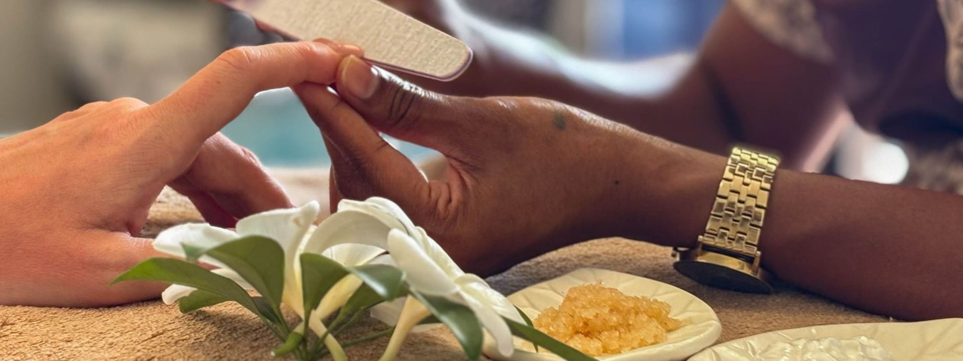 Spa therapist performing a manicure with flowers and creams at The Joy Spa, The Naviti Resort - Fiji