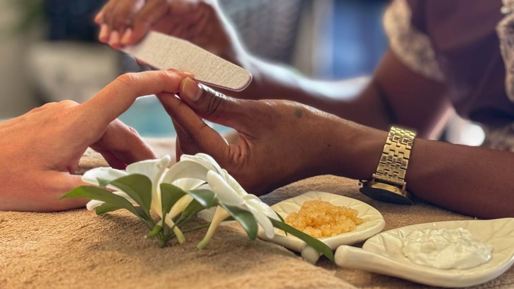Spa therapist performing a manicure with flowers and creams at The Joy Spa, The Naviti Resort - Fiji.