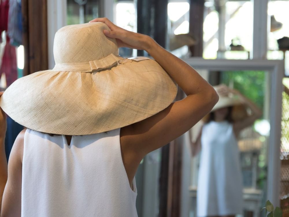 A lady in a hat looking at herself in a mirror at Marbella Club