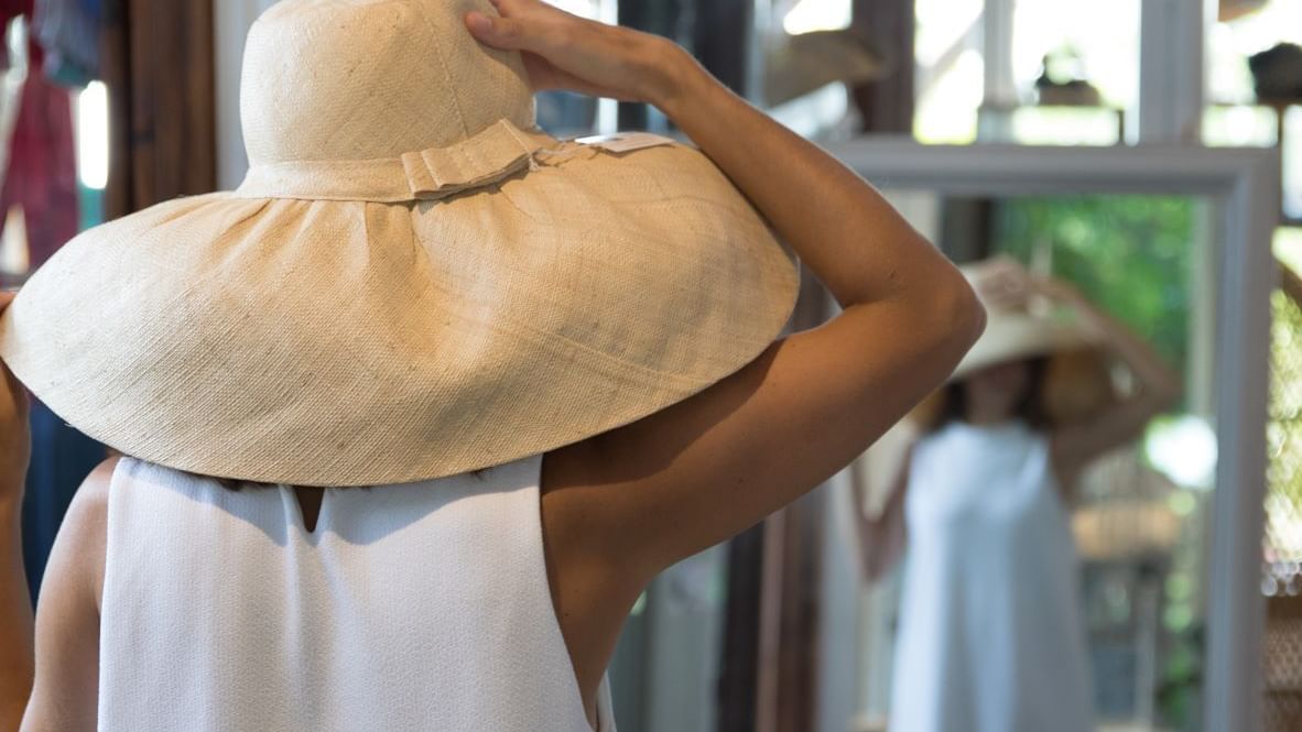 A lady in a hat looking at herself in a mirror at Marbella Club
