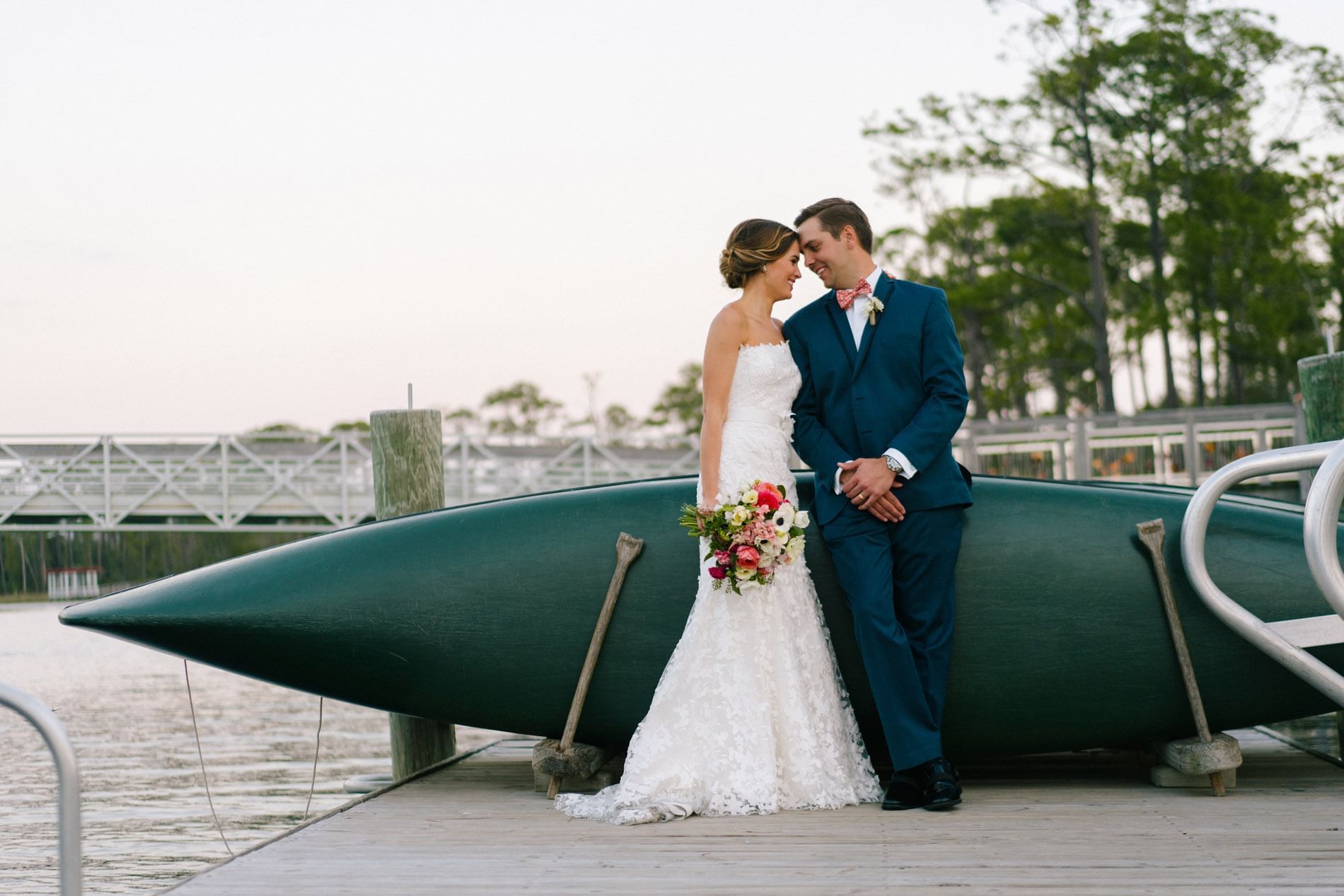 A wedding couple standing near a boat at WaterColor Inn