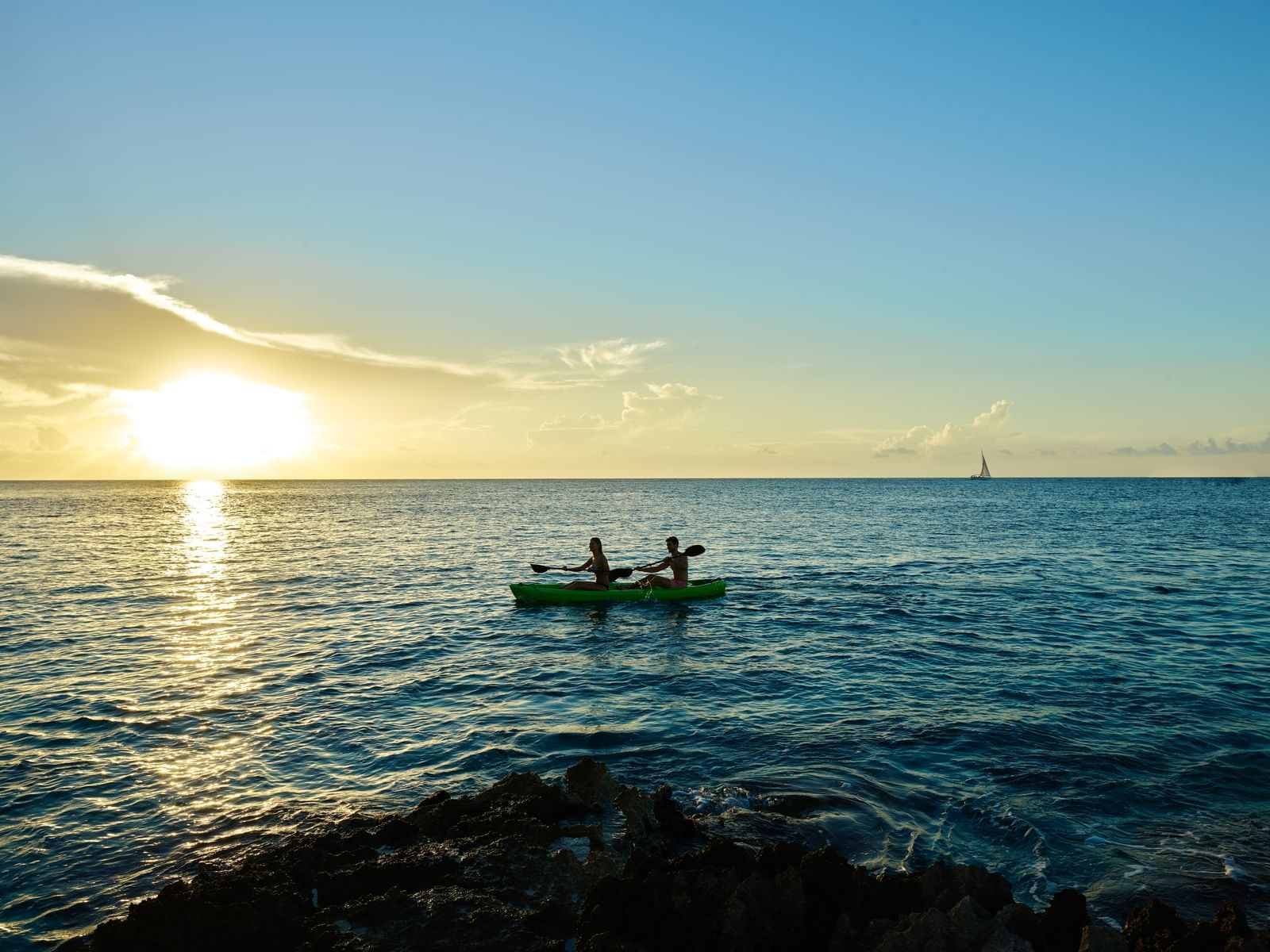 Two people in a kayak paddling on the sea at sunset near The Explorean Resorts