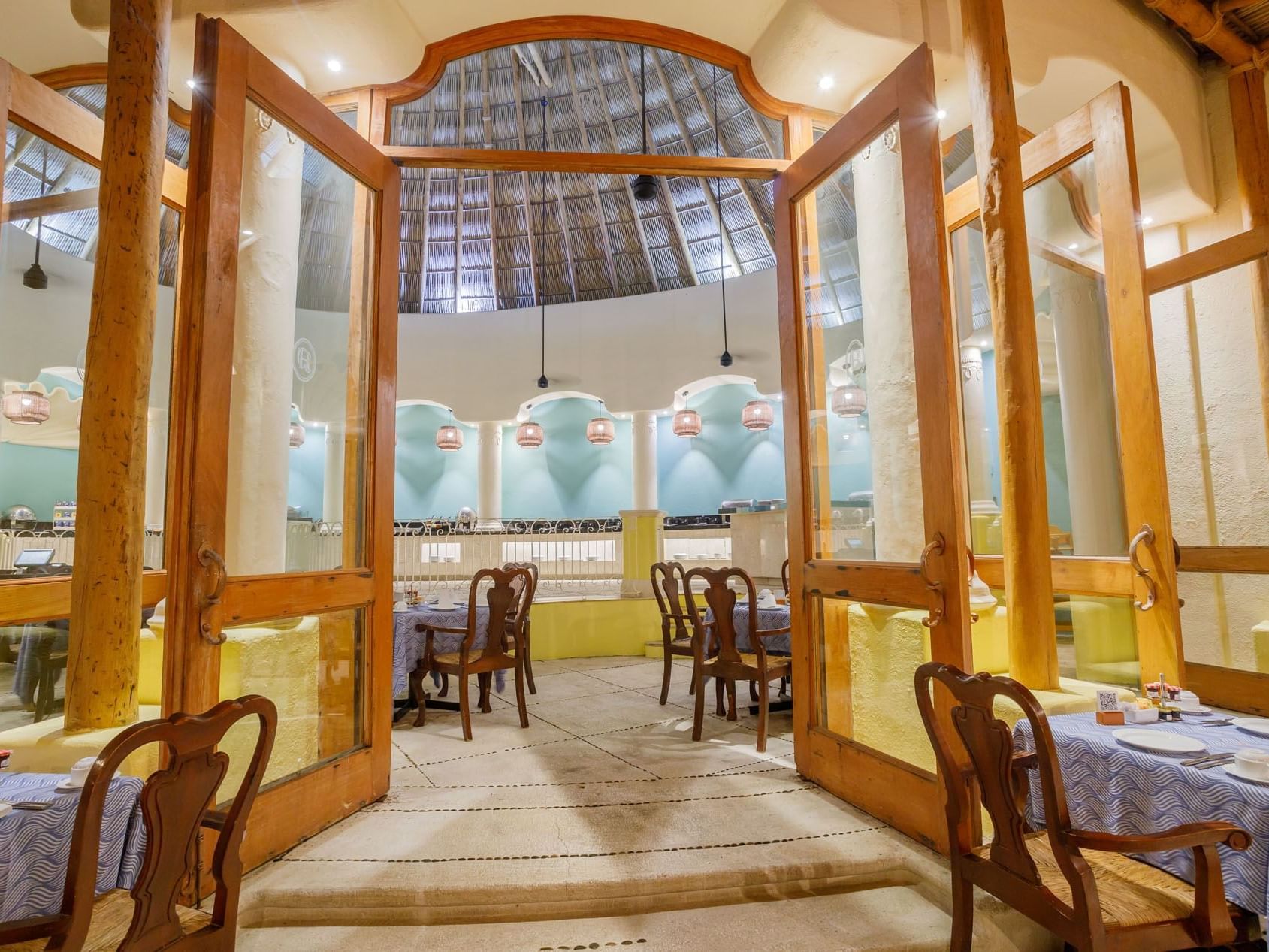 Tierra Mia wooden doors opening into a bright restaurant with classic blue table linens at Quinta Real Acapulco