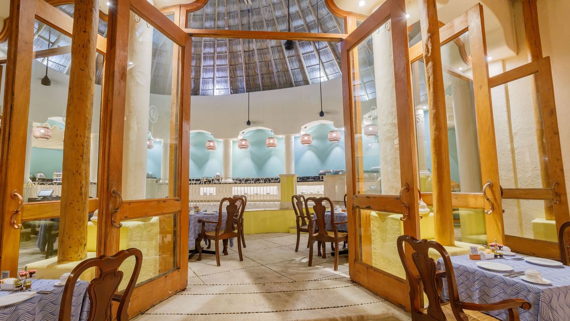 Tierra Mia wooden doors opening into a bright restaurant with classic blue table linens at Quinta Real Acapulco