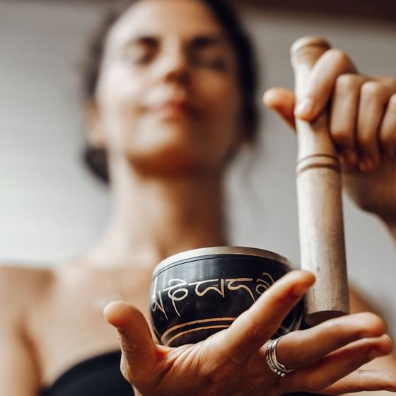 A guest holds a beautiful Tibetan singing bowl at a wellness activity in Retreat group at the Ibagari Hotel