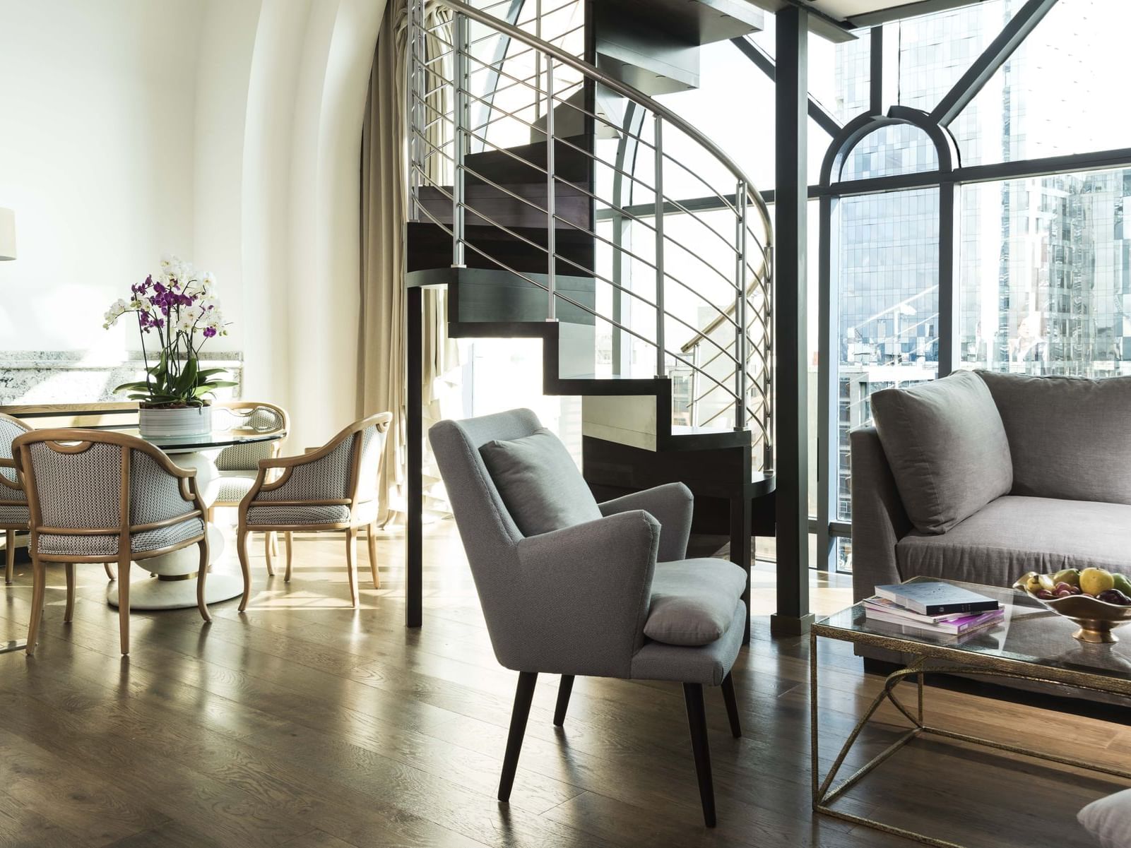 Salón con mesa, sillas, sofá y escalera de caracol en Loft Marquis del Hotel Marquis Reforma en Ciudad de México.