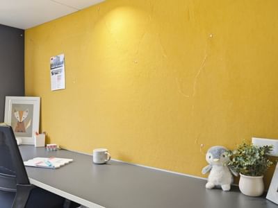 Yellow office wall with desk, chair, and personal items at UniLodge Auckland City.