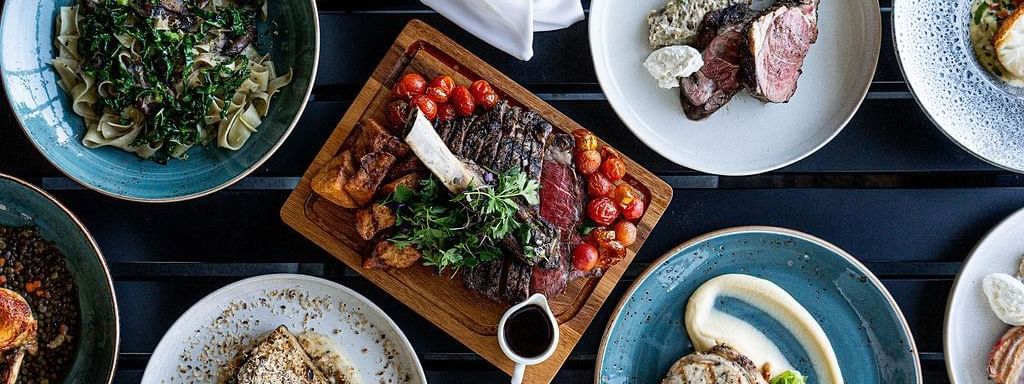 A vibrant array of gourmet dishes, including steak and pasta, served in The Cellar Kitchen at Novotel Barossa Valley Resort