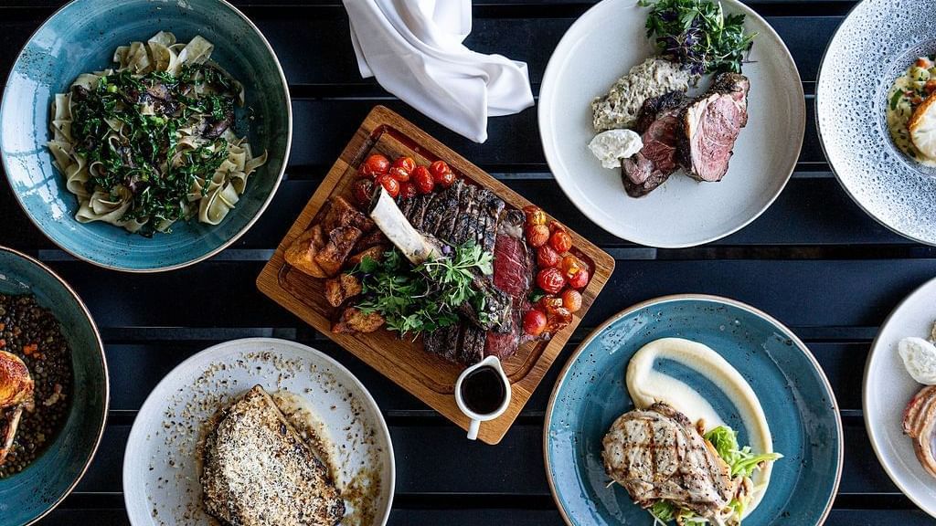 A vibrant array of gourmet dishes, including steak and pasta, served in The Cellar Kitchen at Novotel Barossa Valley Resort