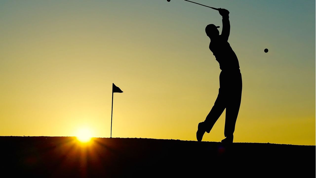 Silhouette of man playing golf during sunrise