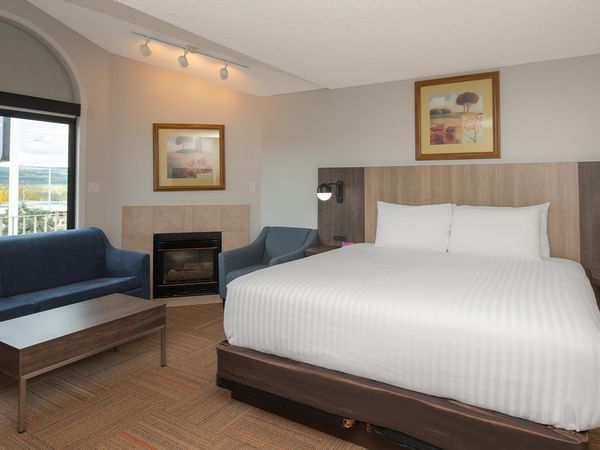 Spacious suite with king bed, blue sofa, fireplace, and mountain views.