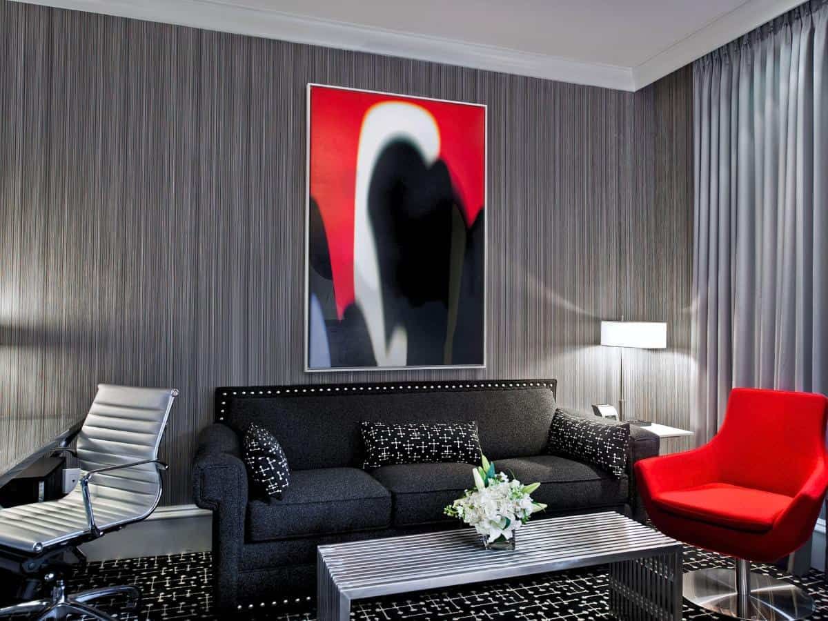 A modern lobby lounge with a gray sofa, red armchair, and abstract artwork
