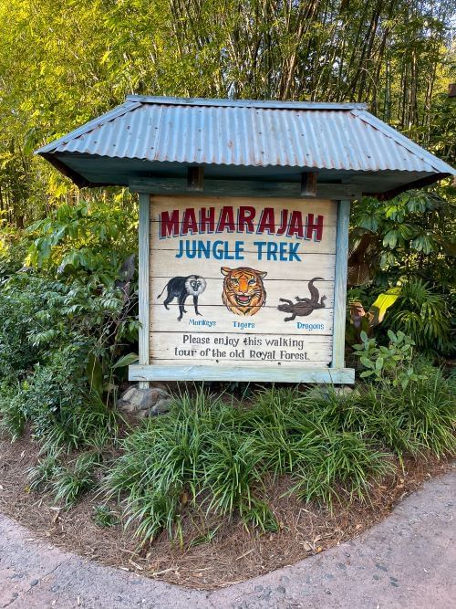 A sign that reads Maharajah Jungle Trek with painted images of a monkey, tiger, and dragon. Animal Kingdom’s Maharajah Jungle Trek is a quiet walking trail with lush scenery, providing a quiet retreat for navigating Disney theme parks as an introvert.