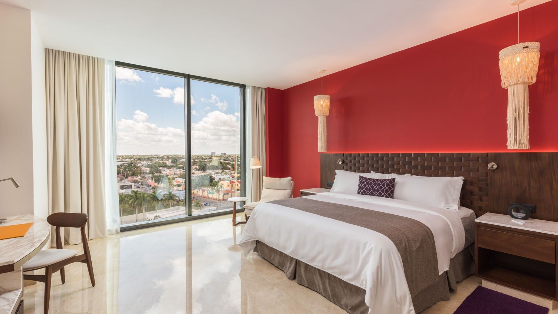 King Deluxe Superior with a vibrant red wall, white linens, and sunlit panoramic windows at Camino Real Merida