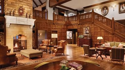 Cozy, wood-paneled lobby, with plush leather armchairs and a warm, lit fireplace at the Sewanee Inn