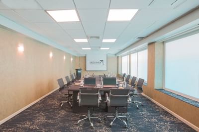 Boardroom set-up with projector screen and carpeted floors in Neptune at Hotel Los Delfines & Casino