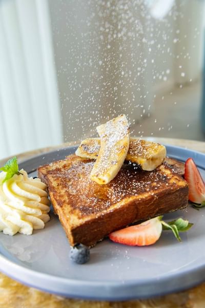 French toast with bananas and strawberries on a blue plate at Ellipse Grace Bay