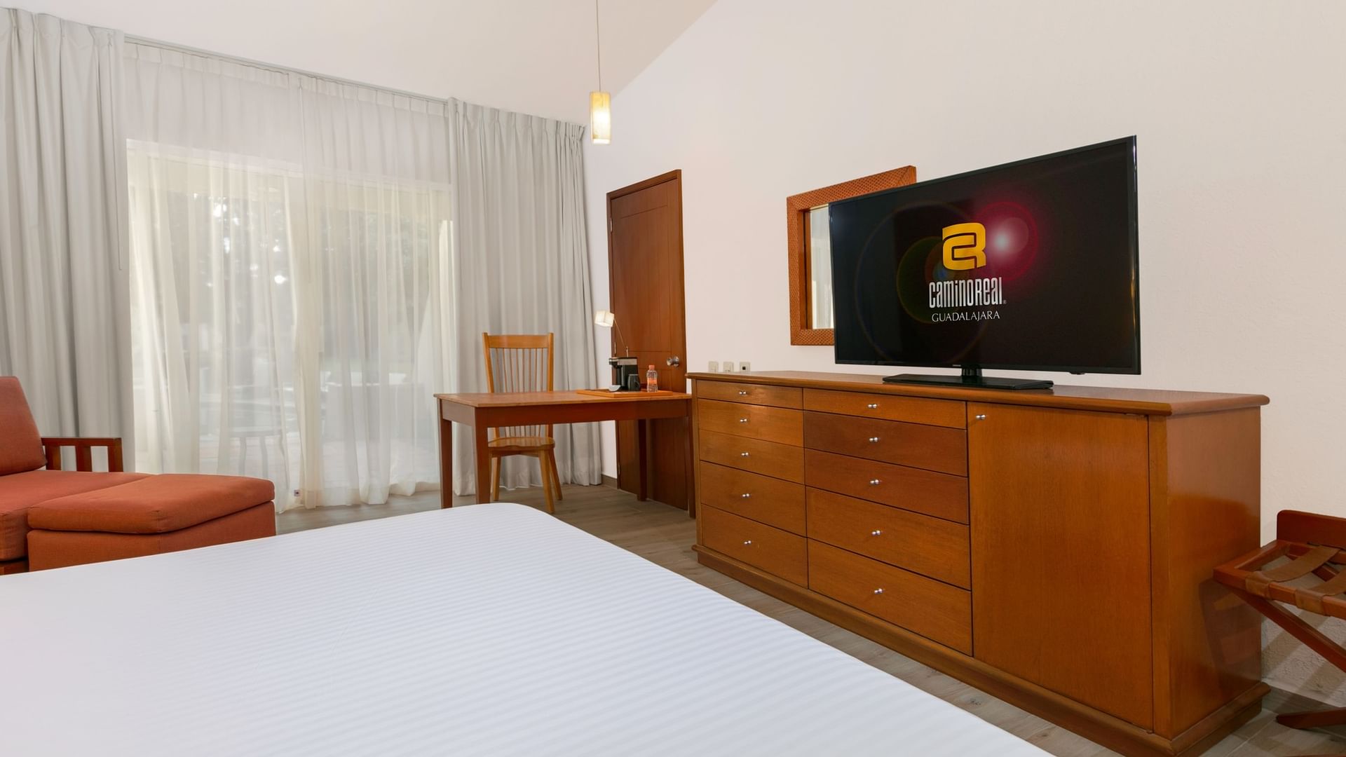 King Presidential Suite room with large bed, wooden dresser, and flat screen TV at Camino Real Guadalajara in Zapopan