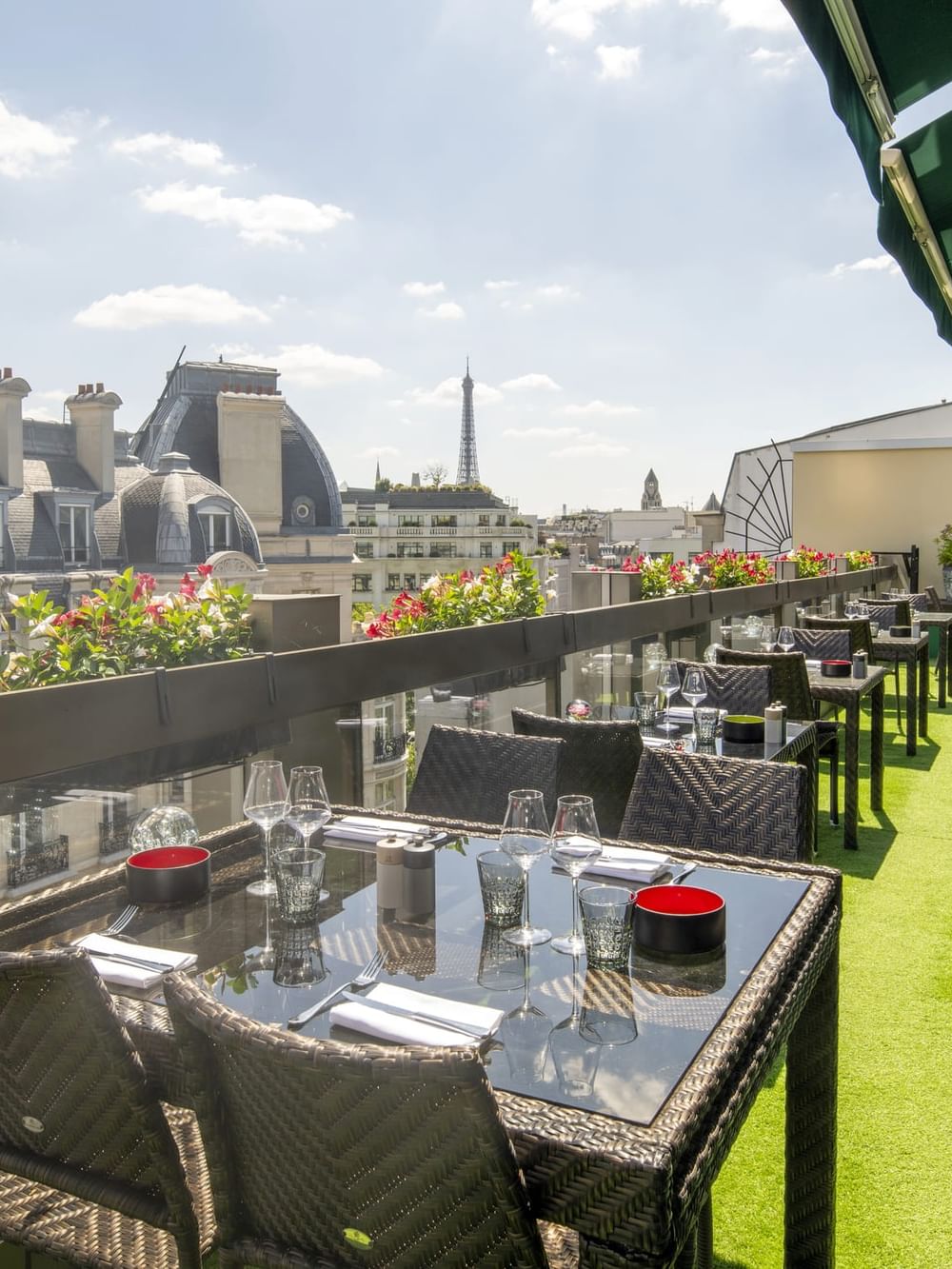 Tables with wine glasses on a grass terrace under a green awning in Terrace Le W at Warwick Paris Champs Elysées