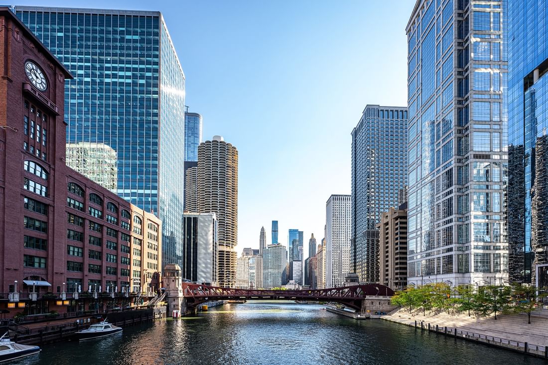 Skyline view of Chicago River with bridge and boats under a clear blue sky near Warwick Allerton Chicago