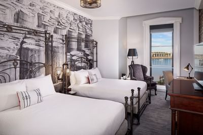 Work desk & couch facing beds in River View Room with Two Queens and French Balcony at River Street Inn