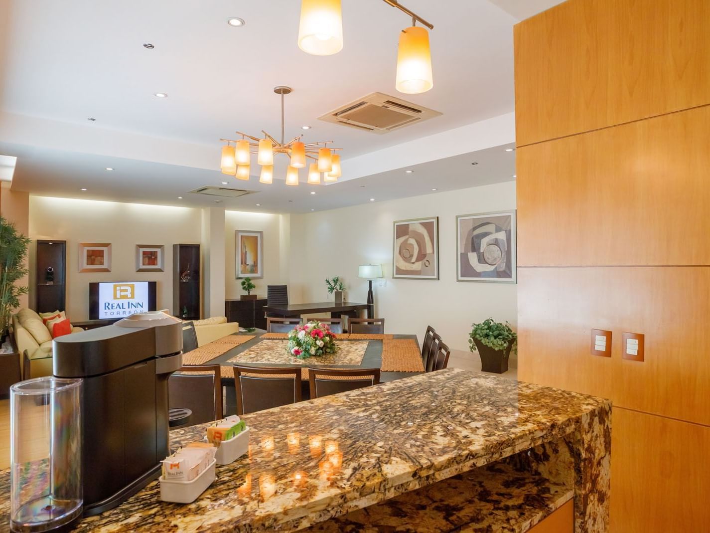 King Presidential Suite dining and kitchen area with granite breakfast bar and elegant pendant lighting at Real Inn Torreon