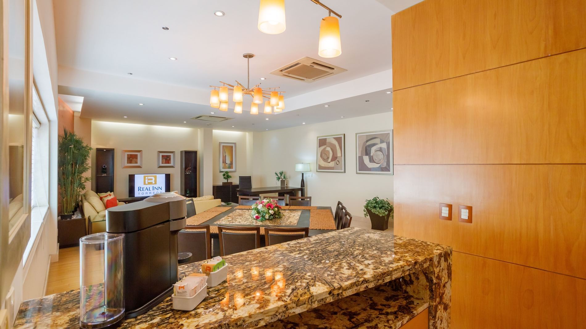 King Presidential Suite dining and kitchen area with granite breakfast bar and elegant pendant lighting at Real Inn Torreon
