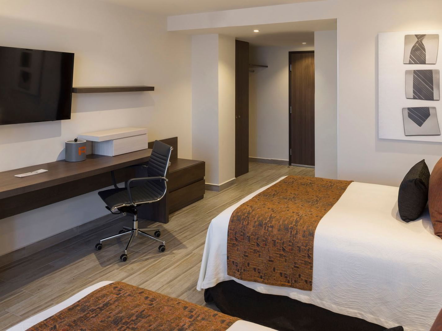 King Deluxe room with a long wooden desk, ergonomic chair, and minimalist wall art by the bed at Real Inn Celaya
