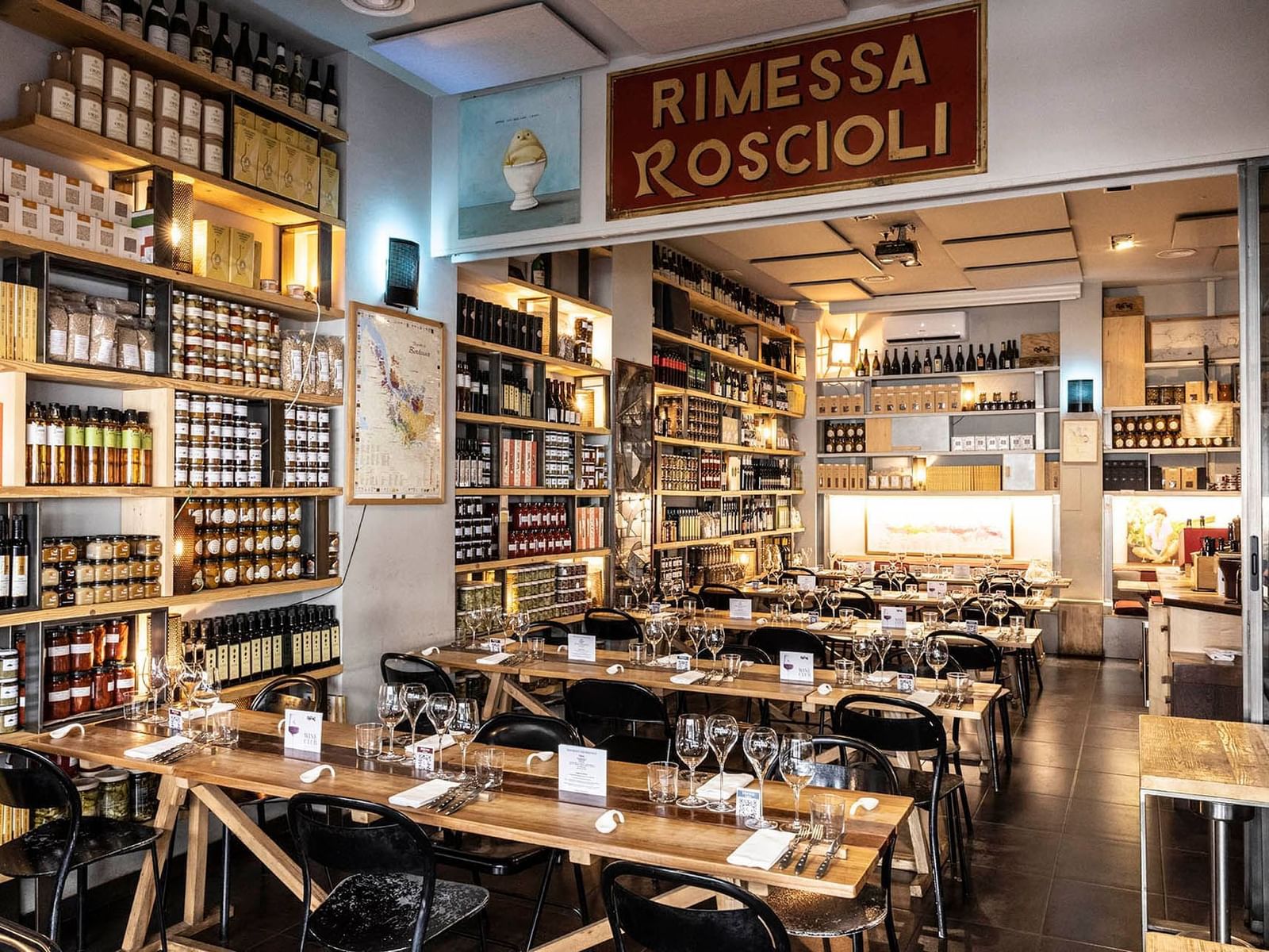 Rimessa Roscioli with wooden tables set for dining, surrounded by wine bottles near The Guardian Hotel