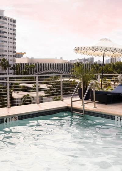 Refreshing rooftop swimming pool at Riviera Hotel South Beach with a white umbrella and views of the city skyline
