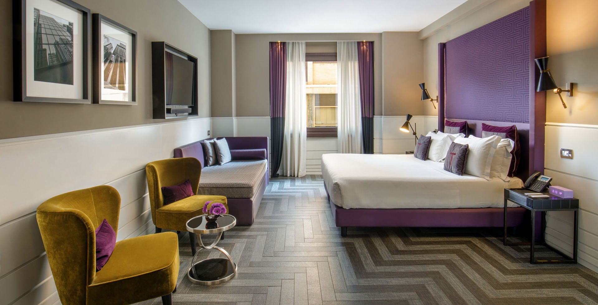 King Bed Family Room at Tribune Hotel Rome with spacious layout, modern design, comfortable king bed, sofa lounge, and stylish seating area with vibrant décor.