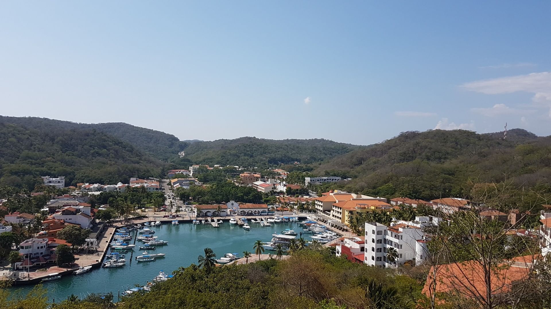 La Crucecita with buildings and lush greenery surrounding a marina filled with boats near Camino Real Zaashila Huatulco