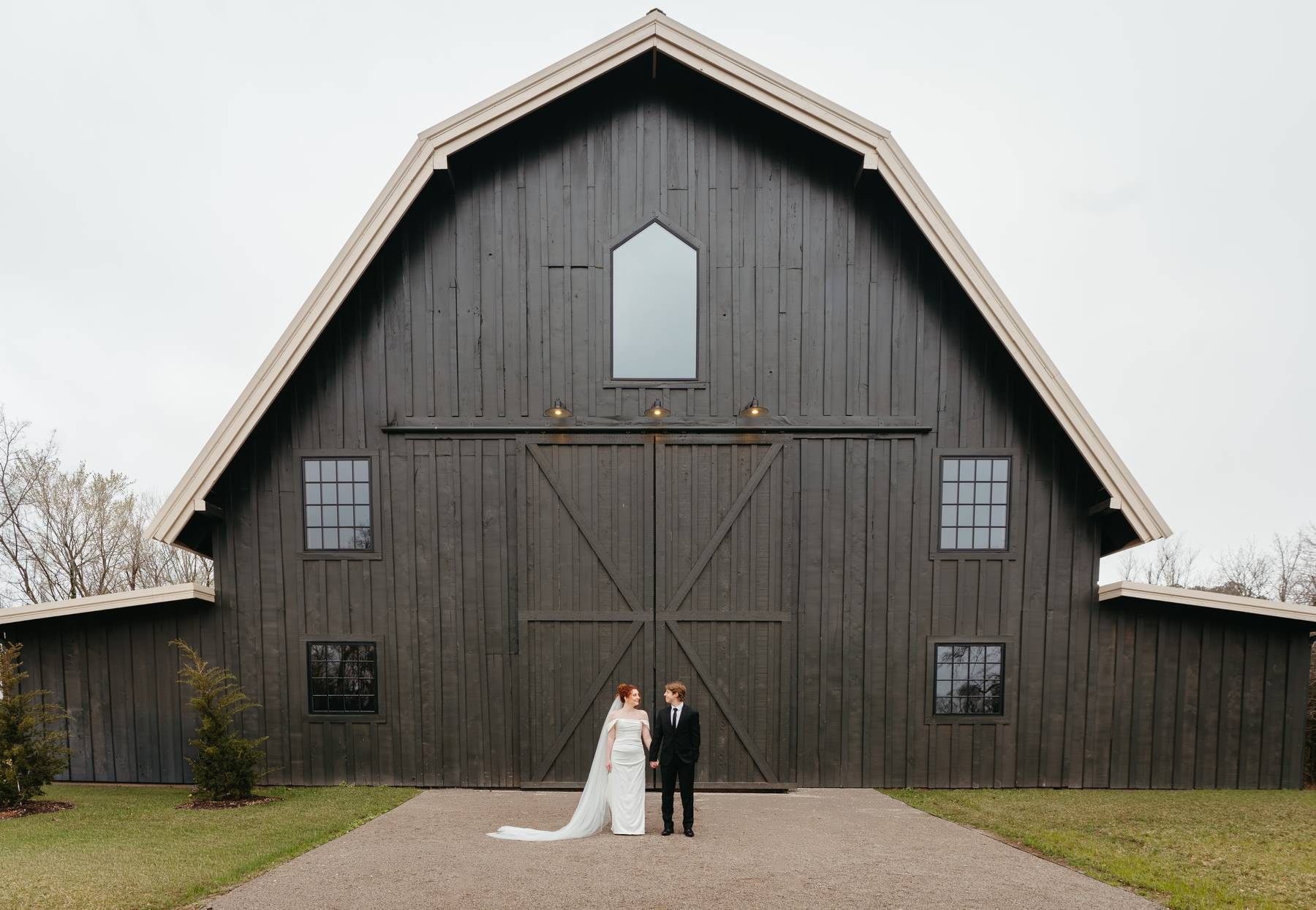 A bride and groom standing at the altar surrounded by loved ones in a rustic barn venue