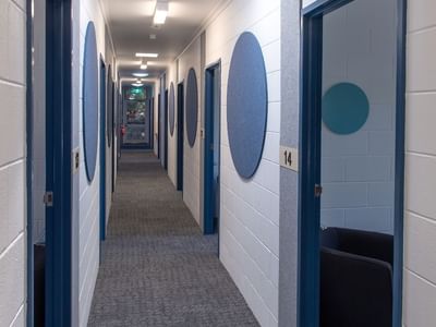 Long hallway with blue doors and chairs at La Trobe University - Orde House.