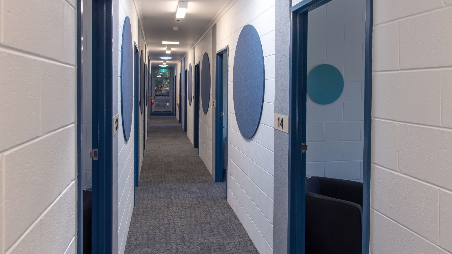 Long hallway with blue doors and chairs at La Trobe University - Orde House.