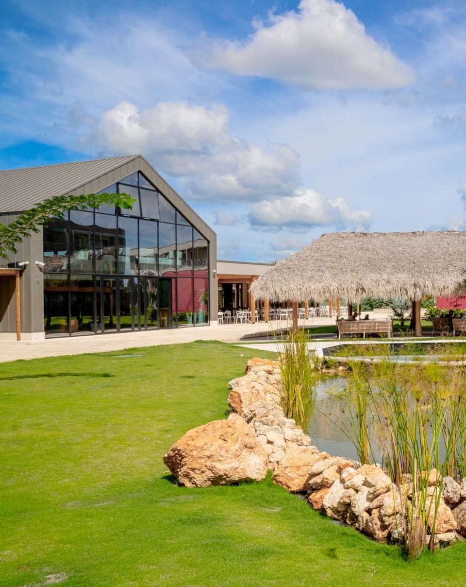 Lush resort grounds at The Hub Acunmeyda, featuring a central pond, thatched cabana, and modern event pavilion