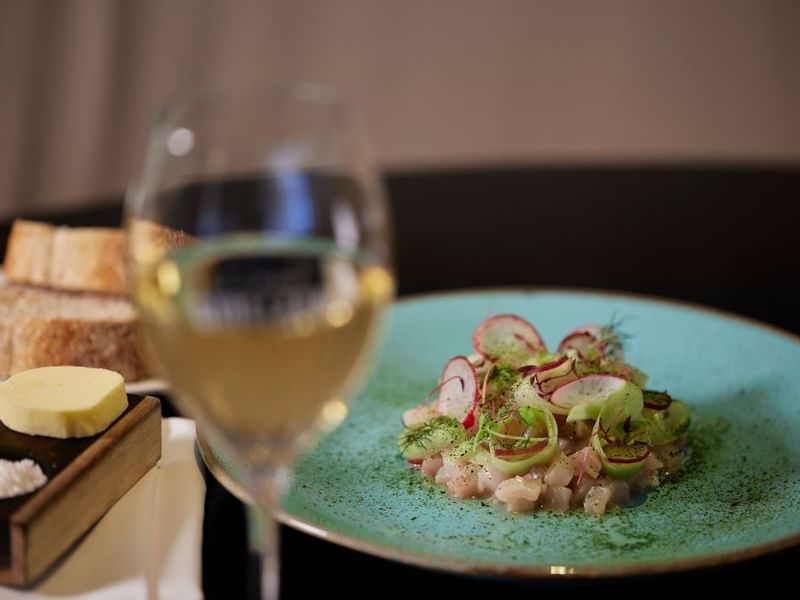 Gourmet dish with radish garnish and a glass of wine in Bistro Guillaume at Crown Metropol Perth