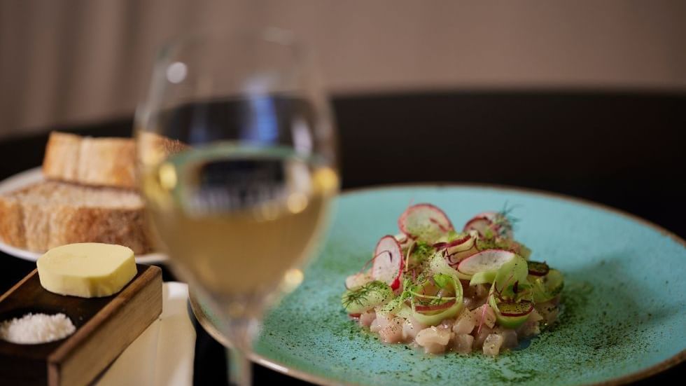 Gourmet dish with radish garnish and a glass of wine in Bistro Guillaume at Crown Metropol Perth