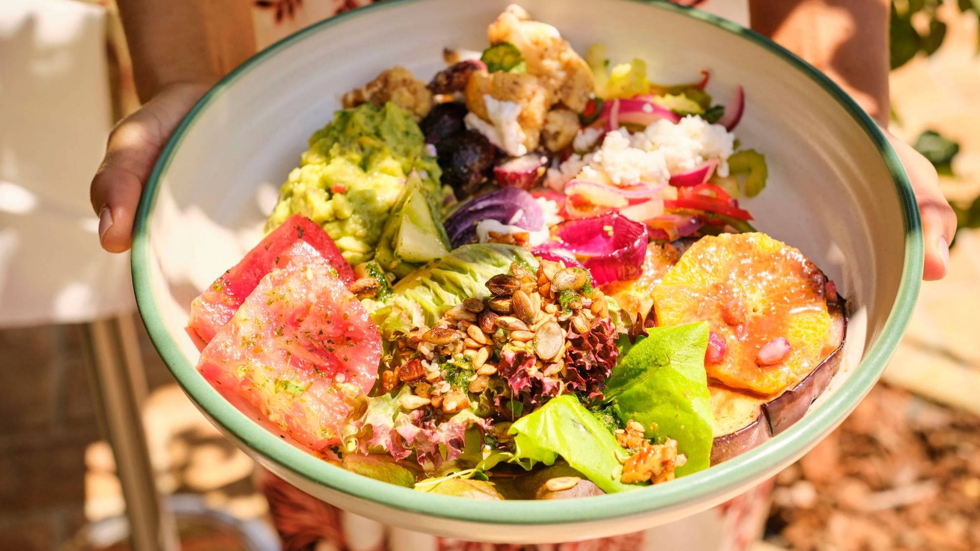 Person holding a bowl of vibrant salad with watermelon at El Olivar by Chef Andrés in Marbella Club, Marbella.